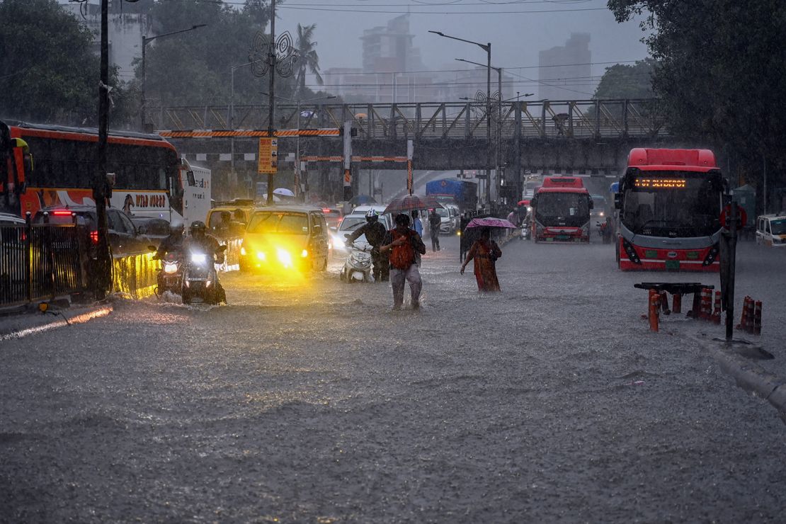 People wade through waterlogged road at Gandhi Market in the Sion area after heavy rain on May 25, in Mumbai, India.