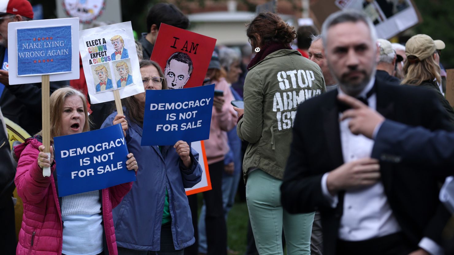 Demonstrators protest as a guest arrives outside Trump National Golf Club, where the top 220 holders of the president’s personal $TRUMP meme coin were invited to private dinner.