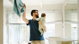 Father holding his baby and taking a towel to dry him after bath time in the bathroom
