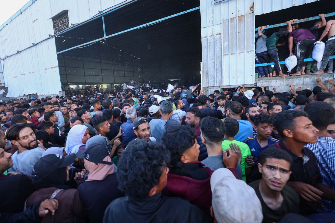 Displaced Palestinians ferry bags of food aid as they storm a World Food Programme warehouse in Deir Al-Balah in the central Gaza Strip on May 28, 2025.