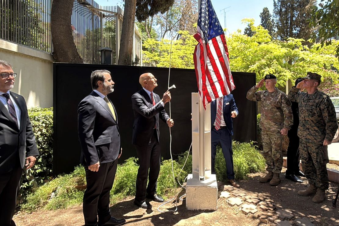El ministro de Asuntos Exteriores sirio, Assaad al-Shibani, observa al enviado especial de EE.UU. para Siria, el embajador en Turquía, Thomas Barrack, izar la bandera de Ee.UU. en la residencia del embajador en Damasco durante una ceremonia oficial celebrada el 29 de mayo de 2025.