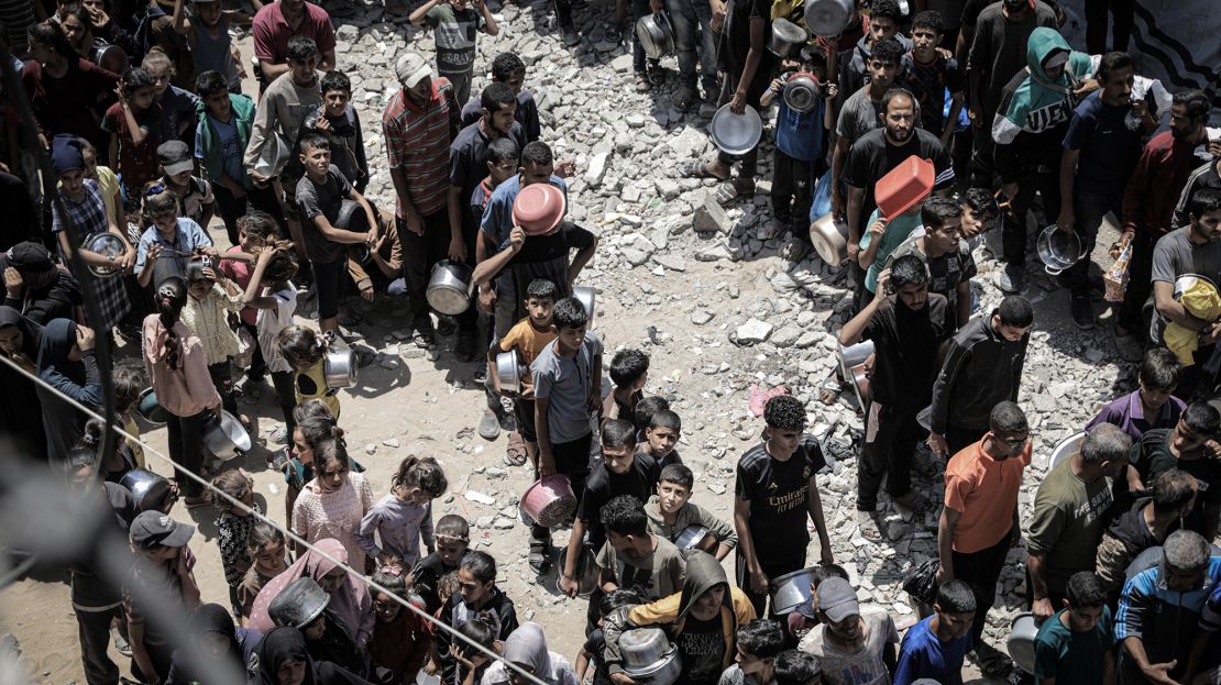 Displaced Palestinians line up in long queues to receive food distributed by aid organizations at Sheikh Radwan neighborhood in Gaza City, Gaza on Tuesday.