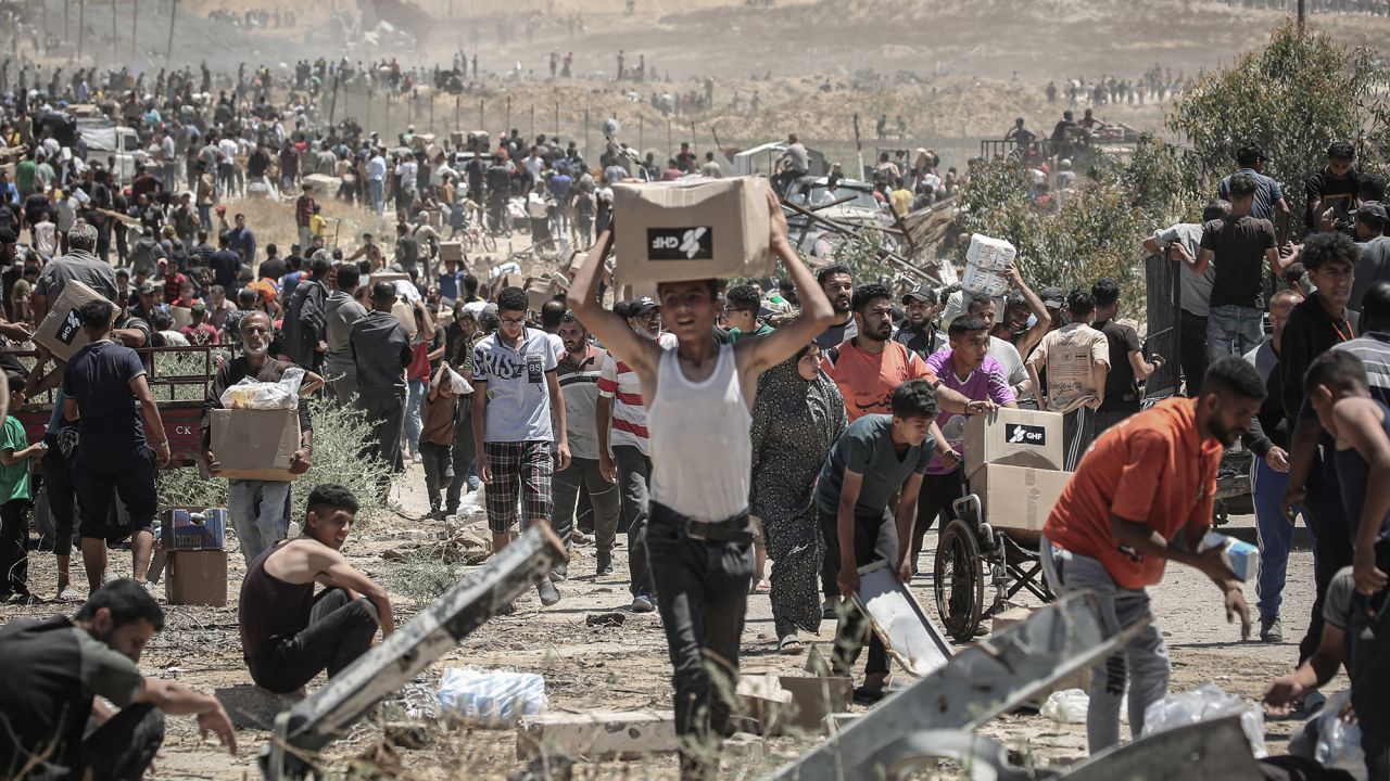 Palestinians carry boxes of humanitarian aid collected from a distribution center in the Netzarim Corridor, central Gaza Strip, on Thursday.