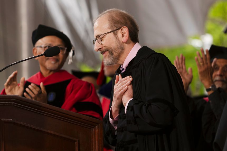 Harvard University President Alan Garber holds his hand to his heart in gratitude as he gets a standing ovation Thursday from the commencement crowd in Harvard Yard in Cambridge.