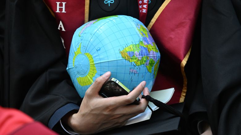 A graduate of the Kennedy School of Government carries an inflatable globe during commencement exercises at Harvard University on May 29, 2025, in Cambridge, Massachusetts.