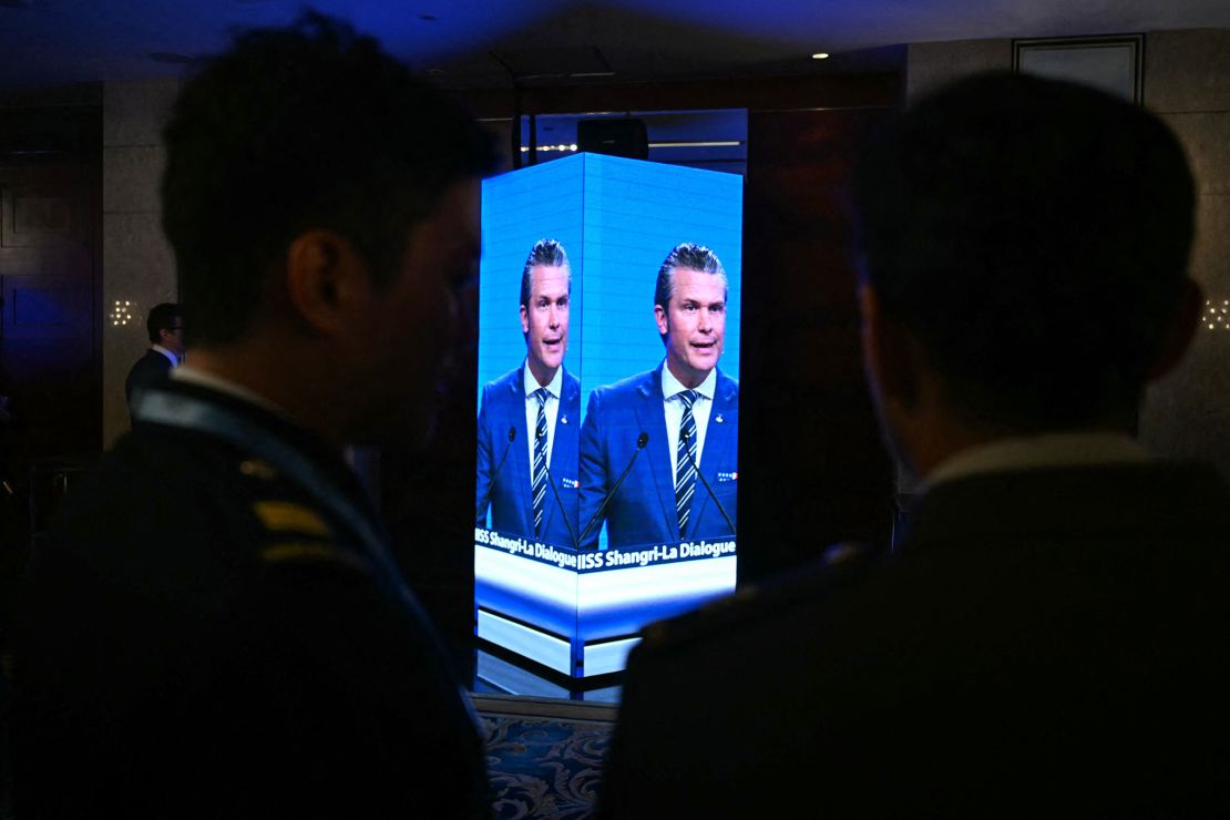 Attendees outside the ballroom watch on a screen as US Secretary of Defense Pete Hegseth delivers an address at the Shangri-La Dialogue Summit in Singapore on May 31, 2025.