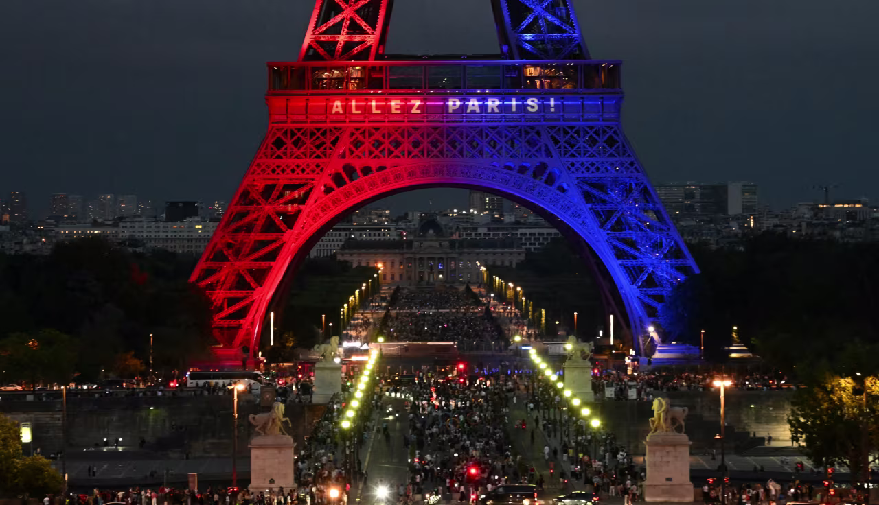 Crowds gather under the illuminated Eiffel Tower in Paris on Saturday.