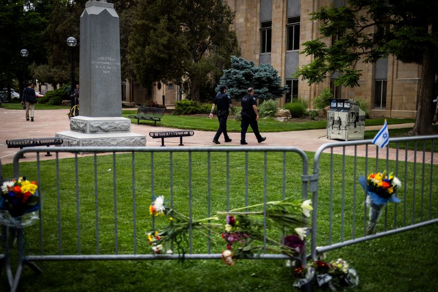 Police officers walk past a barricade adorned with flowers outside the Boulder County Courthouse in Boulder, Colorado, on Monday.