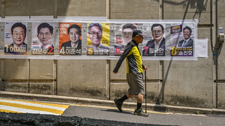 A man walks past posters of candidates during the presidential election in Seoul on June 3, 2025.