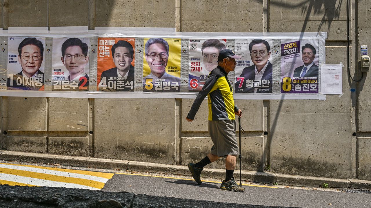 A man walks past posters of candidates during the presidential election in Seoul on June 3, 2025.