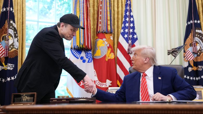 Elon Musk shakes hands with President Donald Trump as they speak to reporters in the Oval Office.