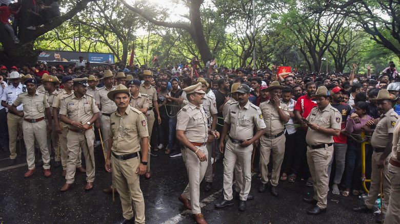 Police stand in front of crowds as fans gather outside the M. Chinnaswamy Stadium to celebrate Royal Challengers Bengaluru winning the Indian Premier League (IPL), in Bengaluru on June 4, 2025. Packed crowds in India celebrating their cricket team's victory ended in a deadly stampede on Wednesday with 11, mainly young, fans crushed to death, the local state's chief minister said. Joyous cricket fans had come out to celebrate and welcome home their heroes, Royal Challengers Bengaluru, after they beat Punjab Kings in the Indian Premier League cricket final the previous night. (Photo by AFP) (Photo by STRINGER/AFP via Getty Images)          