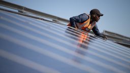 A worker fits solar panels onto frames during construction at South Africa's first municipally owned solar plant, during International World Environment Day, on June 05, 2025, in Atlantis, about 40km from Cape Town.