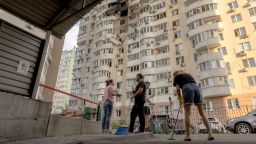 People clean debris in front of a residential building damaged during a Russian air strike in Kyiv on June 6, 2025.
