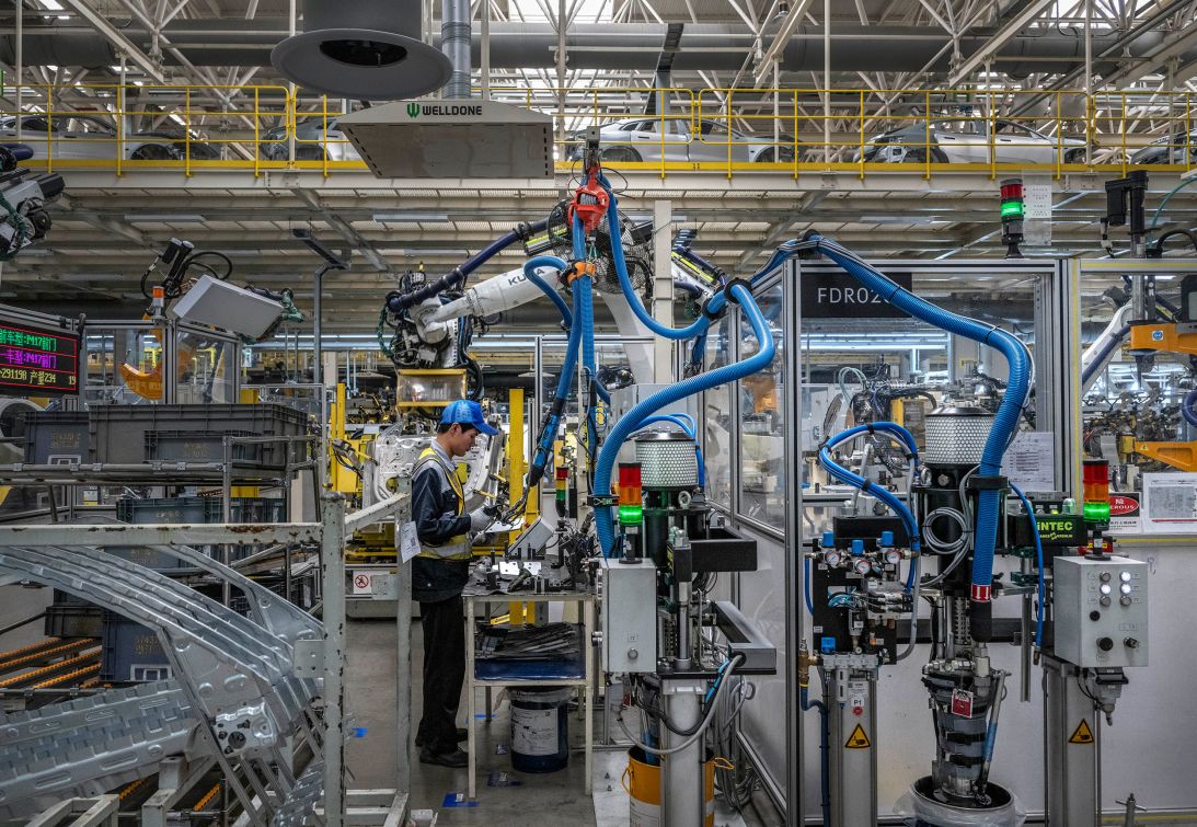 A worker controls a robotic arm on the production line at an electric vehicle factory in Ningbo, China, on May 29.