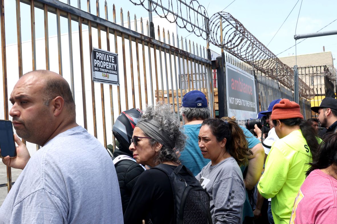 People gather in front of Ambiance Apparel in the garment district of downtown Los Angeles after several employees were taken into custody by federal agents on Thursday, June 5.