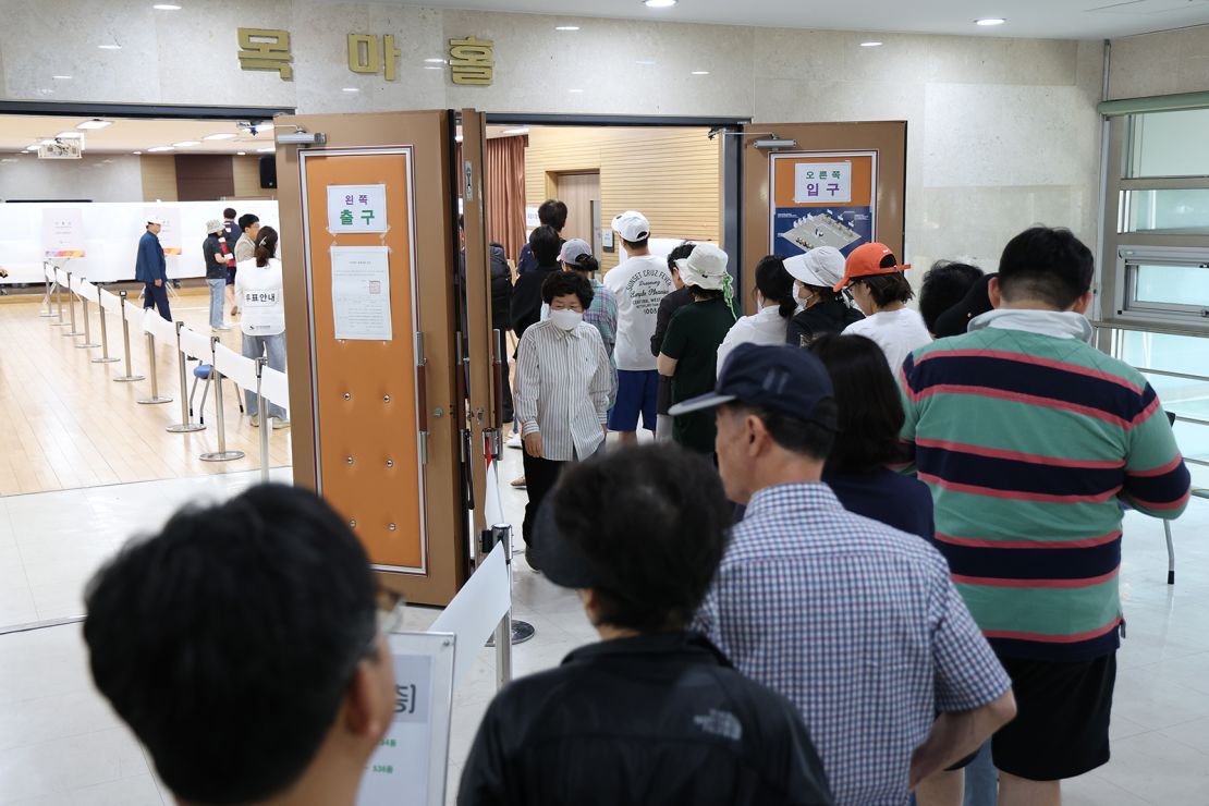 People wait in line to cast their votes for the snap election on Tuesday.