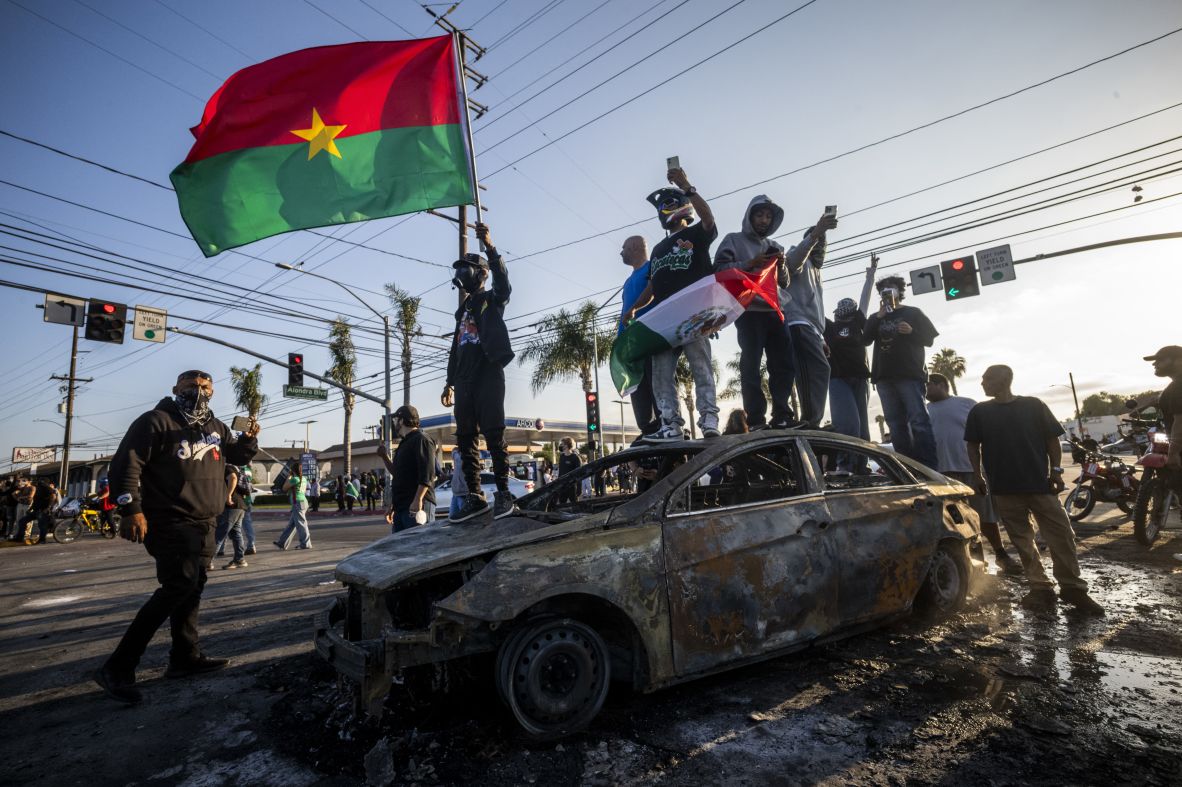 Demonstrators stand on top of a charred vehicle during a protest in the Compton neighborhood of Los Angeles.