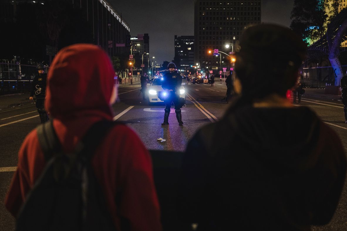 Protesters stand in front of police blocking a bridge over the 101 Freeway on Sunday.