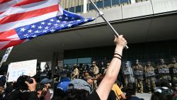A demonstrator holds an upside down US flag as they face California National Guard standing guard outside the Federal Building during a protest in response to federal immigration operations in Los Angeles, on June 9, 2025. US President Donald Trump on June 9 ordered active-duty Marines into Los Angeles, vowing those protesting immigration arrests would be "hit harder" than ever. Protests in Los Angeles, home to a large Latino population, broke out on June 6, triggered by immigration raids that resulted in dozens of arrests of what authorities say are illegal migrants and gang . (Photo by RONALDO SCHEMIDT / AFP) (Photo by RONALDO SCHEMIDT/AFP via Getty Images)