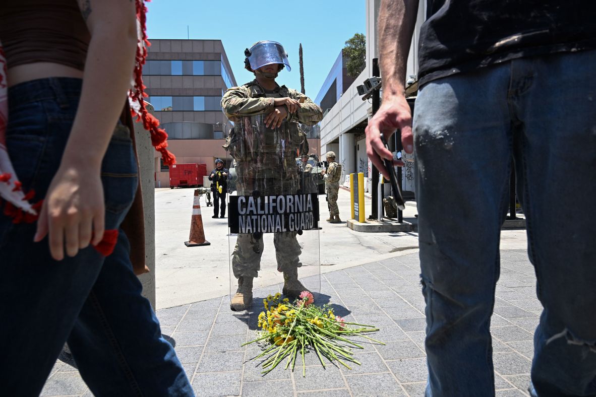 Members of the clergy and other protestors place flowers at the feet of a California National Guardsman stationed outside federal buildings near the Metropolitan Detention Center in Los Angeles on Tuesday.