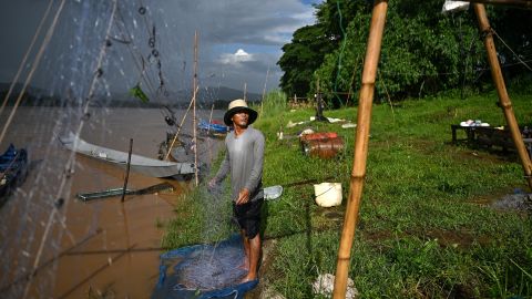 Thai fisherman Sawat Kaewdam sorting his fishing net along the banks of Mekong river in the Golden Triangle region in northern Thailand's Chiang Rai province. A sprawling new mine is gouged into the lush rolling hills of northeast Myanmar, where civil war has weakened the government's already feeble writ, and pollution levels are rising downstream in Thailand.