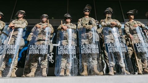  de la Guardia Nacional de California montan guardia frente al Edificio Federal antes de la entrada en vigor del toque de queda en Los Ángeles el 10 de junio de 2025, tras días de protestas en respuesta a las operaciones federales de inmigración que provocaron enfrentamientos en el centro de la ciudad.