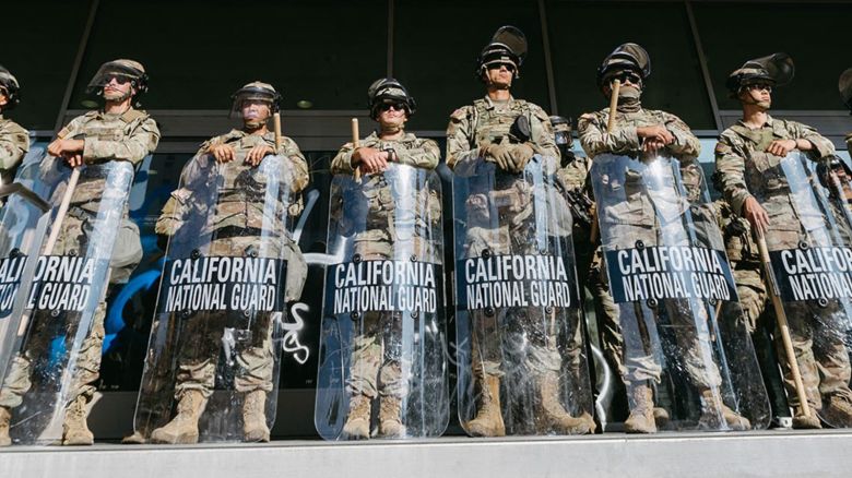  de la Guardia Nacional de California montan guardia frente al Edificio Federal antes de la entrada en vigor del toque de queda en Los Ángeles el 10 de junio de 2025, tras días de protestas en respuesta a las operaciones federales de inmigración que provocaron enfrentamientos en el centro de la ciudad.