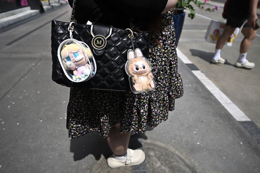 Labubu (R) and CryBaby (L) attached to a shopper's handbag outside the Pop Mart store in Siam Square in Bangkok.