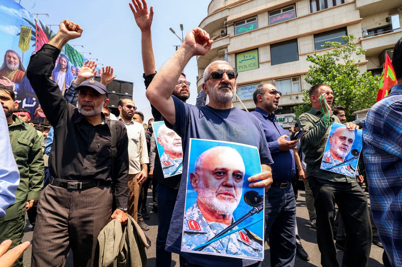 Personas sostienen fotos del general de división Gholam Ali Rashid, comandante superior del Cuerpo de la Guardia Revolucionaria Islámica de Irán, mientras se congregan para protestar contra la ola de ataques israelíes sobre Irán en la Plaza Enghelab, en el centro de Teherán, el viernes.