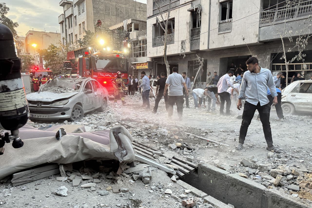 Personas y socorristas se reúnen fuera de un edificio que fue alcanzado por un ataque israelí en Teherán este viernes.