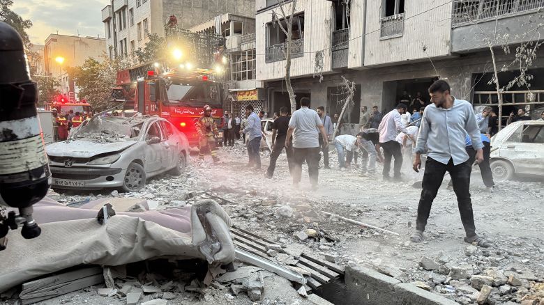 People and first-responders gather outside a building that was hit by an Israeli strike in Tehran on June 13, 2025. Israel hit about 100 targets in Iran on June 13, including nuclear facilities and military command centres and killing senior figures including the armed forces chief and top nuclear scientists. (Photo by MEGHDAD MADADI / TASNIM NEWS / AFP) (Photo by MEGHDAD MADADI/TASNIM NEWS/AFP via Getty Images)          