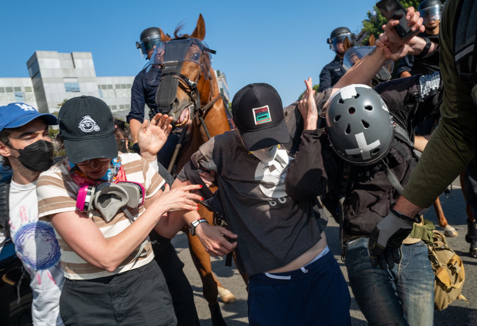LAPD officers on horseback clash with protesters after a series of immigration raids on Sunday.