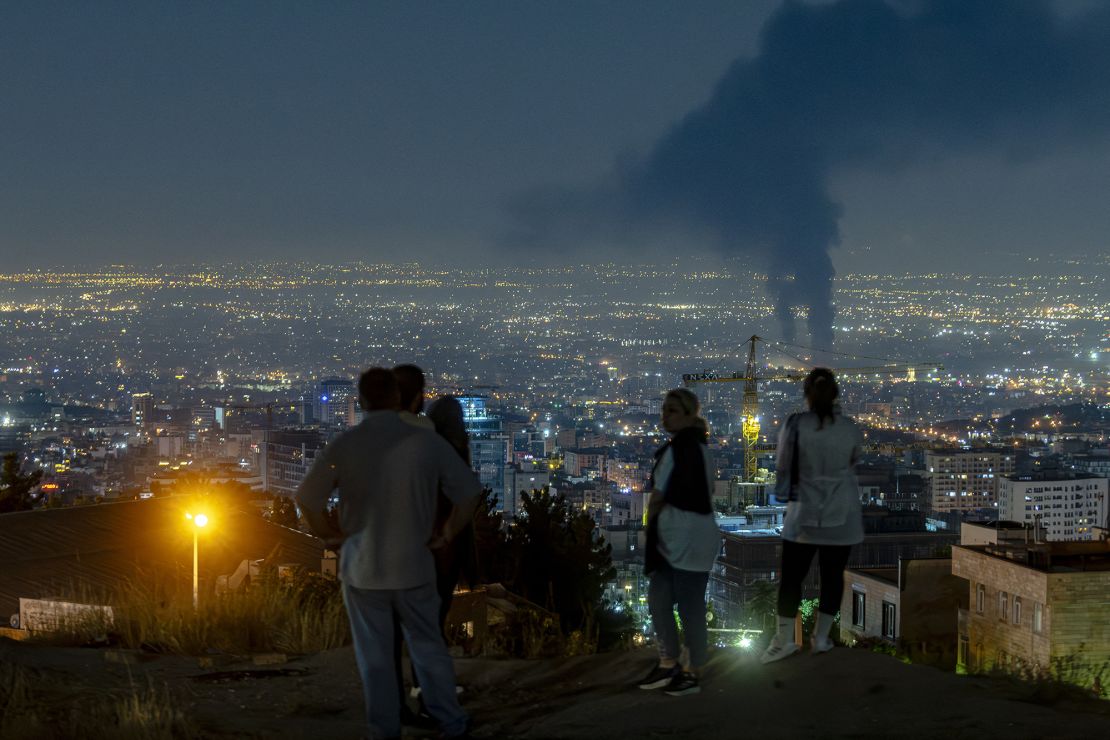 People gather on a hill to watch smoke rising in the distance from an Israeli airstrike in Tehran, Iran, on June 14.