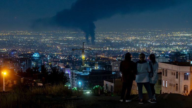 People gather on a hill to watch smoke rising in the distance from an Israeli airstrike in Tehran, Iran, on June 14, 2025. Iran's foreign minister said the country would respond "decisively and proportionally" to a wave of attacks that Israel launched beginning in the early hours of June 13. The attacks targeted multiple military, scientific and residential locations, as well as senior government officials. (Photo by Khoshiran / Middle East Images via AFP) (Photo by KHOSHIRAN/Middle East Images/AFP via Getty Images)          
