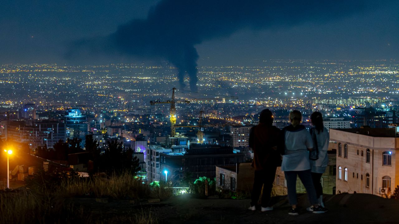 People gather on a hill to watch smoke rising in the distance from an Israeli airstrike in Tehran, Iran, on June 14, 2025. Iran's foreign minister said the country would respond "decisively and proportionally" to a wave of attacks that Israel launched beginning in the early hours of June 13. The attacks targeted multiple military, scientific and residential locations, as well as senior government officials. (Photo by Khoshiran / Middle East Images via AFP) (Photo by KHOSHIRAN/Middle East Images/AFP via Getty Images)          