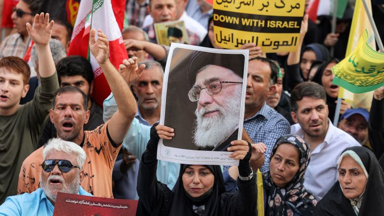A demonstrator holds a picture of Iran's Supreme Leader Ayatollah Ali Khamenei while gathering with others during a rally in solidarity with the government against Israel's attacks on Iran and to mark Eid al-Ghadir, when according to Shiite Muslim belief the Islamic prophet Mohamed designated his nephew and companion Ali ibn Abi Talib as his successor, at Enghelab (Revolution) Square in Tehran on June 14, 2025. (Photo by Atta KENARE / AFP) (Photo by ATTA KENARE/AFP via Getty Images)          