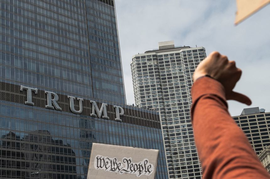 Protesters give a thumbs down gesture while marching past Trump Tower in Chicago, during a day of nationwide "No Kings" demonstrations held on June 14.
