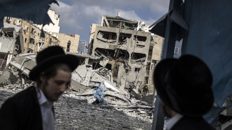 TOPSHOT - Ultra-Orthodox Jewish men inspect the damage at the site of an Iranian missile strike in Bnei Brak, east of Tel Aviv, on June 16, 2025. Iran unleashed a barrage of missile strikes on Israeli cities early on June 16, after Israel struck military targets deep inside Iran, with both sides threatening further devastation. (Photo by JOHN WESSELS / AFP) (Photo by JOHN WESSELS/AFP via Getty Images)          