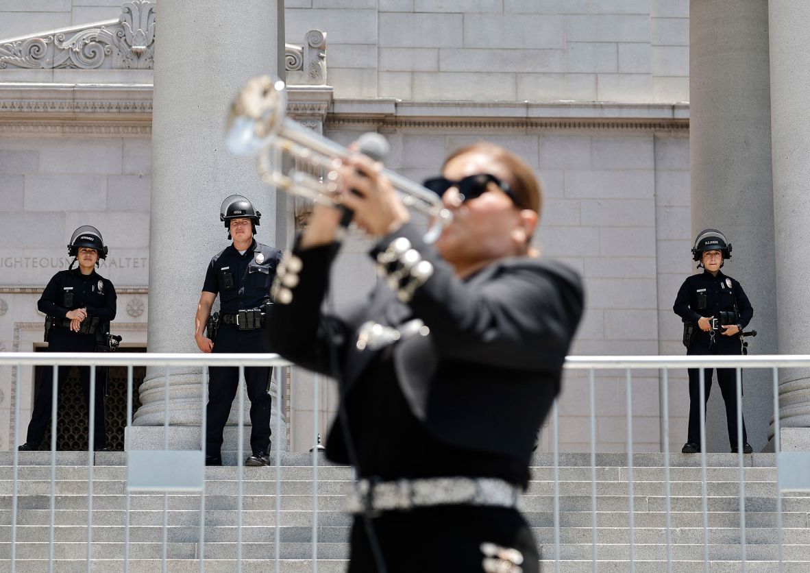 Maricela Martinez of the mariachi band Mariachi Lindas Mexicanas performs during a protest by mariachi and folklorico dancers outside City Hall in Los Angeles on Wednesday, June 11, as police officers keep watch.