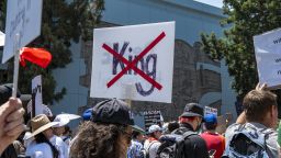 A protester holds a sign with the word "King" crossed out during the "No Kings" rally in Los Angeles, California on June 14, 2025. The coordinated day of action was timed as a direct counter to Donald Trump's highly publicized celebration marking the U.S. Army's 250th anniversary and his own 79th birthday, which included military-style displays in Washington, D.C. Protesters denounced the militarization of democracy, anti-immigrant policies, and what they see as the growing normalization of authoritarian behavior under Trump's leadership. (Photo by Lauren Puente / Middle East Images via AFP) (Photo by LAUREN PUENTE/Middle East Images/AFP via Getty Images)