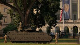 Una gran pancarta con la imagen del presidente Donald Trump cuelga frente al Departamento de Agricultura, cerca de donde se exhibe un vehículo de combate Bradley del Ejército antes del desfile militar del sábado.