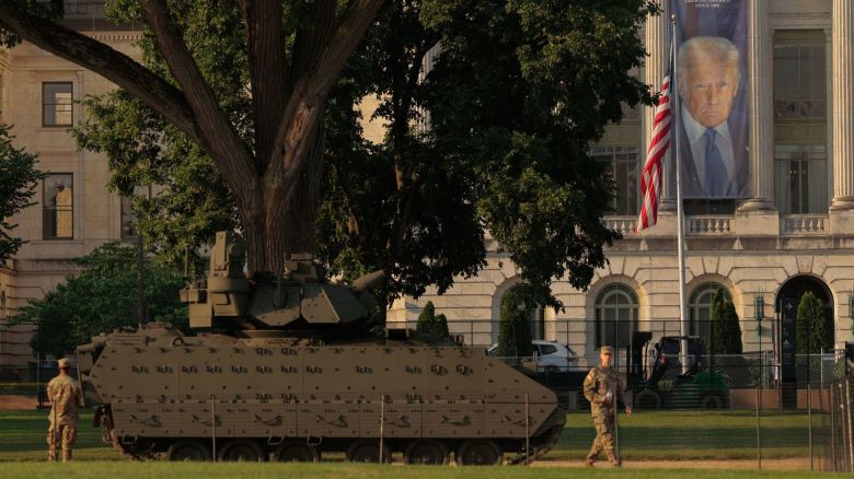 Una gran pancarta con la imagen del presidente Donald Trump cuelga frente al Departamento de Agricultura, cerca de donde se exhibe un vehículo de combate Bradley del Ejército antes del desfile militar del sábado.