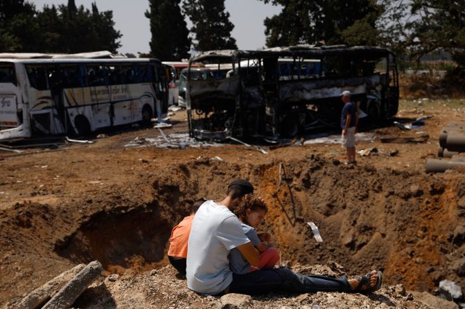 People look at a crater in the ground after a missile strike in Herzliya, Israel, on Tuesday, June 17.