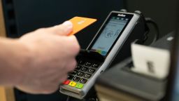 SYMBOL - 17 June 2025, Bavaria, Munich: A person holds their credit card up to a card reader at a self-service checkout in an Edeka supermarket to pay. Photo: Leonie Asendorpf/dpa (Photo by Leonie Asendorpf/picture alliance via Getty Images)