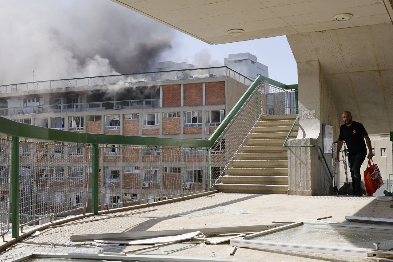 A man carries bags as smoke billows from a building at Soroka Hospital in Beer Sheva on Thursday.