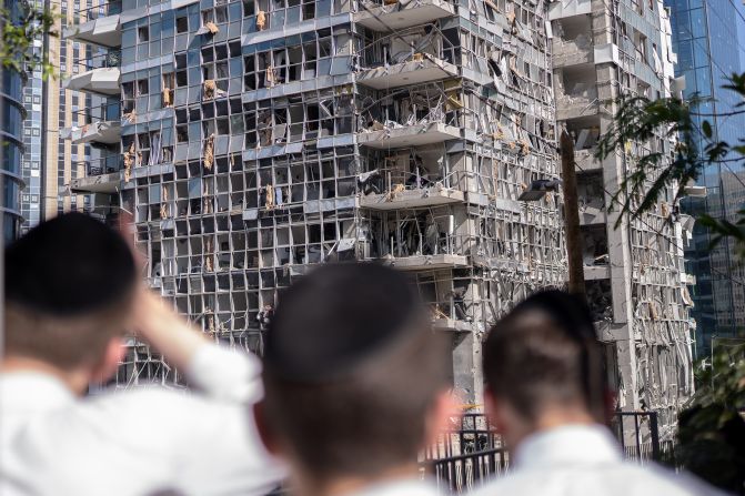 People stand in front of a building damaged by an Iranian missile attack in Ramat Gan, Israel, on Thursday, June 19.