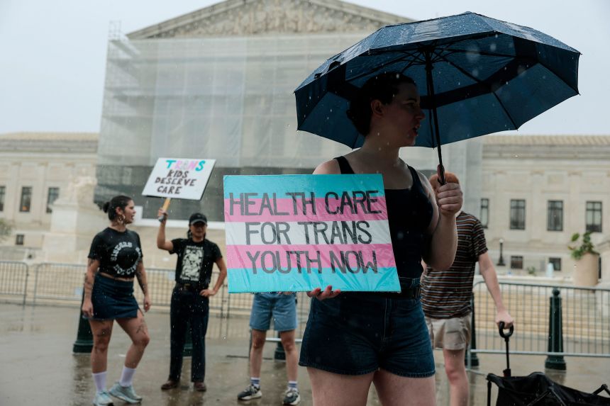 A protester holds a sign in support of gender-affirming care for transgender youth outside of the US Supreme Court Building on June 18 in Washington, DC.