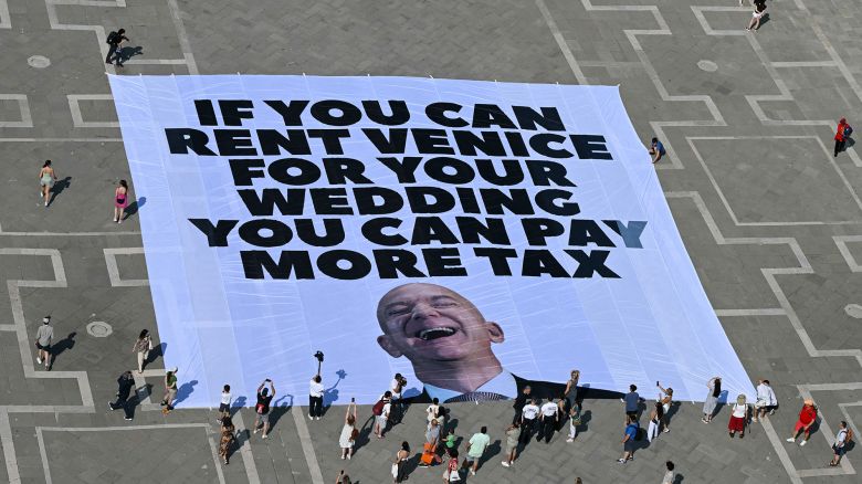 Activists of international environmental group Greenpeace deploy a giant banner displaying a picture of Jeff Bezos and reading "If you can rent Venice for your wedding you can pay more tax" at St Mark square  in Venice on June 23, 2025. Venice will host the wedding of Amazon Founder and CEO Jeff Bezos and journalist Lauren Sanchez before the end of the month with more than 200 guests expected to attend. (Photo by Stefano Rellandini / AFP) (Photo by STEFANO RELLANDINI/AFP via Getty Images)          