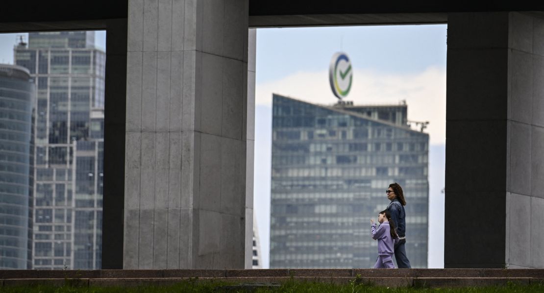 A woman and a girl walk past Sber bank's headquarters in Moscow on June 25, 2025.